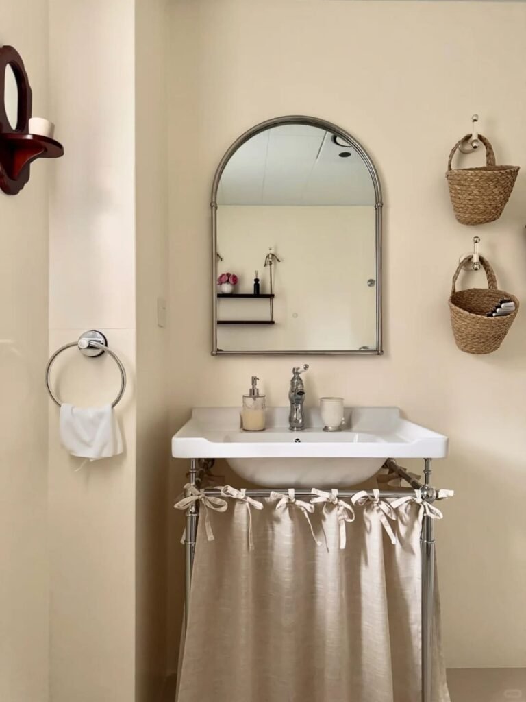 English cottage bathroom with a skirted vanity and soft floral fabric hiding storage.