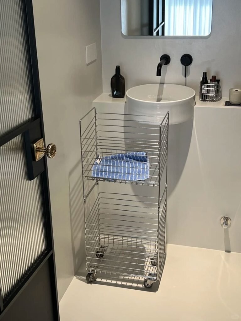 Slim rolling storage cart tucked beside a vanity for extra bathroom organization.