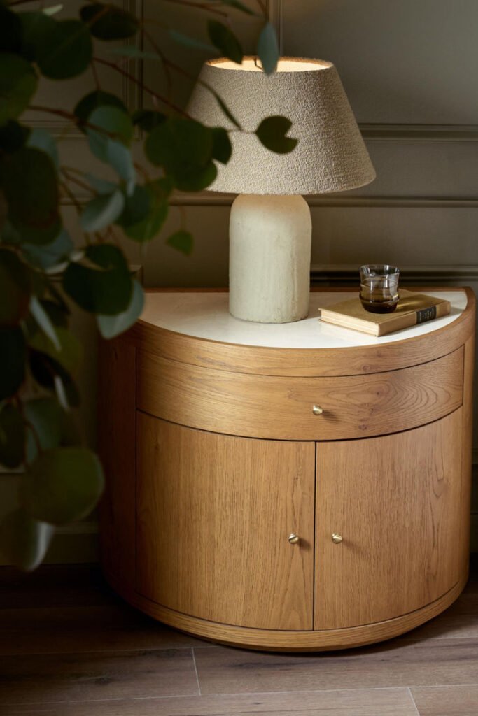 A unique half-moon shaped bedside table with a semi-circle design, flush against the wall to save space.