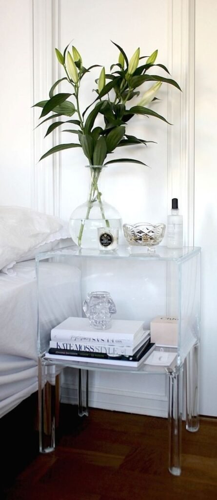 A transparent, clear acrylic lucite bedside table that creates an invisible, lightweight look in a contemporary bedroom.