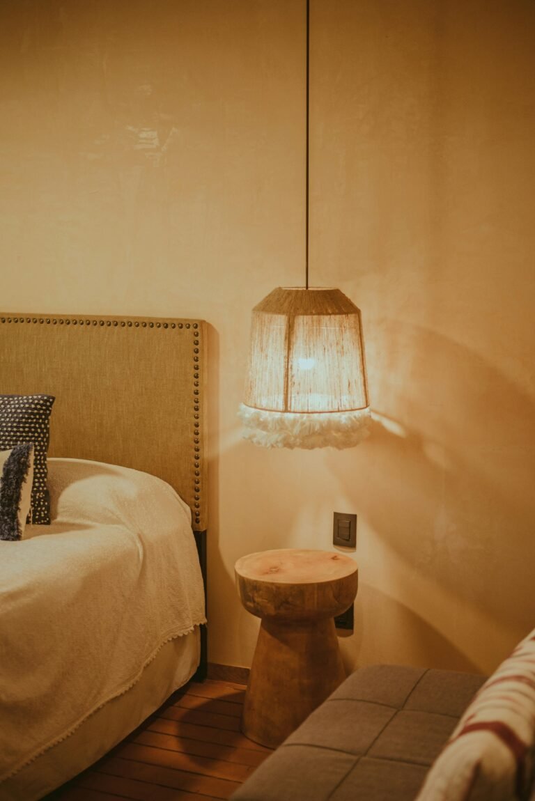 Modern minimalist bedroom with an organic light wood nightstand and a soft-glow ceramic lamp beside a white cloud bed.