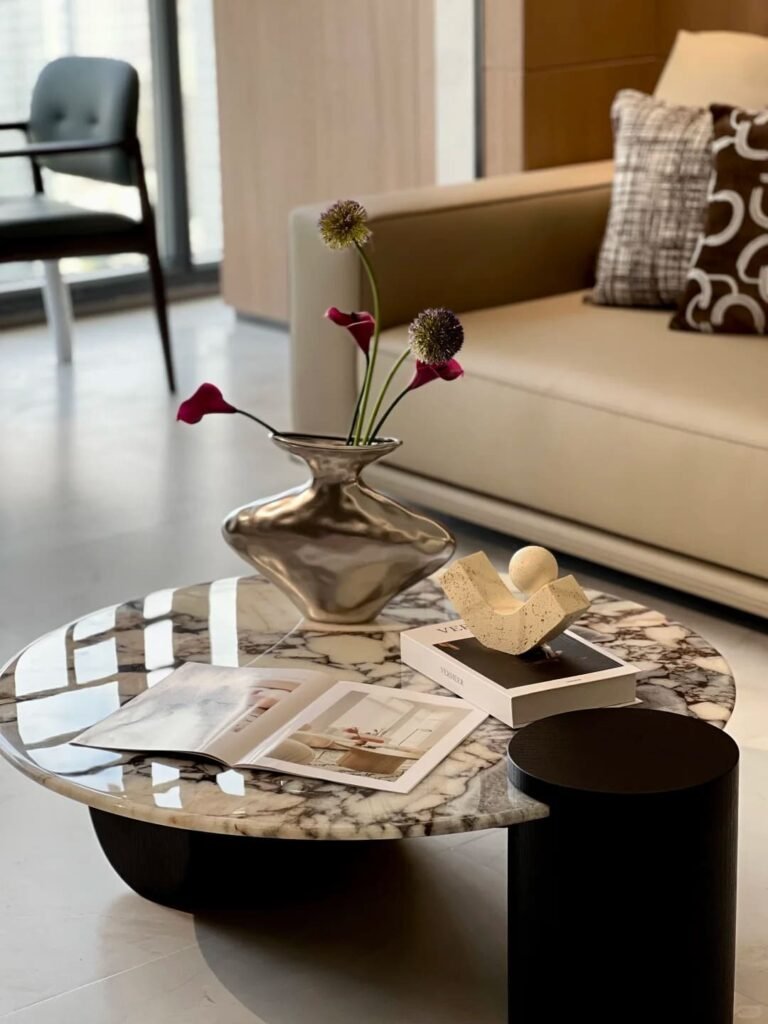 Minimalist coffee table with a single flower stem displayed in a sculptural glass vase.
