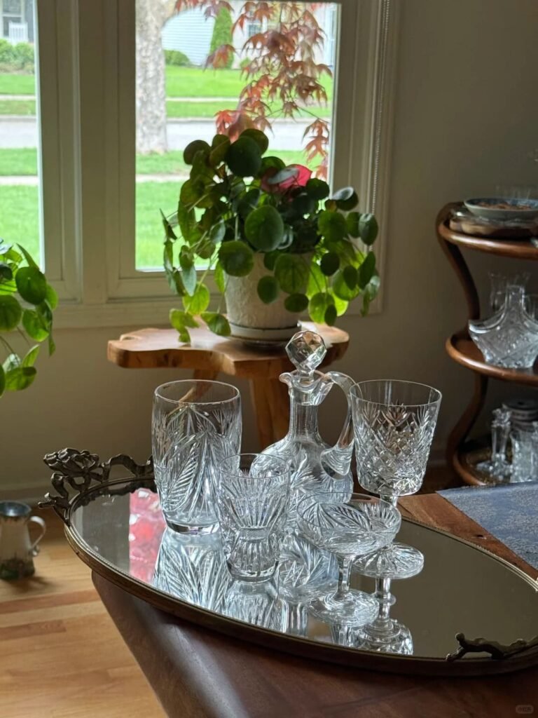 Vintage mirrored tray reflecting candles and decorative accessories.
